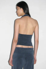 Back view of a woman wearing a dark blue halter neck crop top and dark blue wide leg pants.