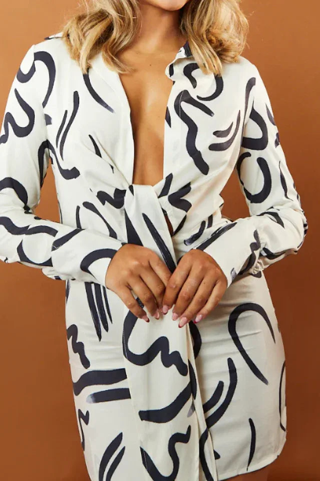 Close-up of the neckline and tie-front detail of a cream and black abstract print dress