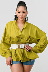 Woman wearing a lime green peplum top with ruffled detailing, balloon sleeves, and a white belt.