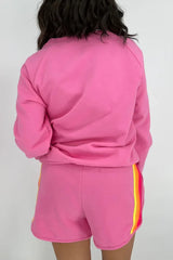 Back view of a woman wearing a pink crew neck sweatshirt and matching pink shorts.