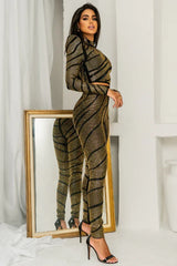 Profile view of a woman showcasing the fitted silhouette of a black and gold rhinestone embellished set.