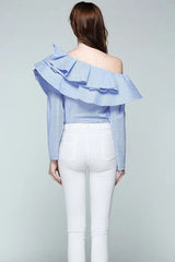 Back view of a woman wearing a blue and white striped off-the-shoulder ruffled blouse and white pants.