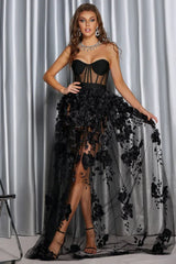 Full-length view of a woman wearing a black formal dress with a sweetheart neckline and floral overlay