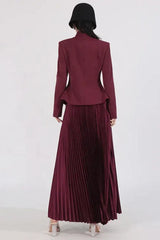 Back view of a woman wearing a burgundy jacket and pleated skirt, with a black hat obscuring her face.
