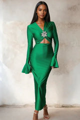 Woman wearing a long green satin dress with long flared sleeves and a cutout waist