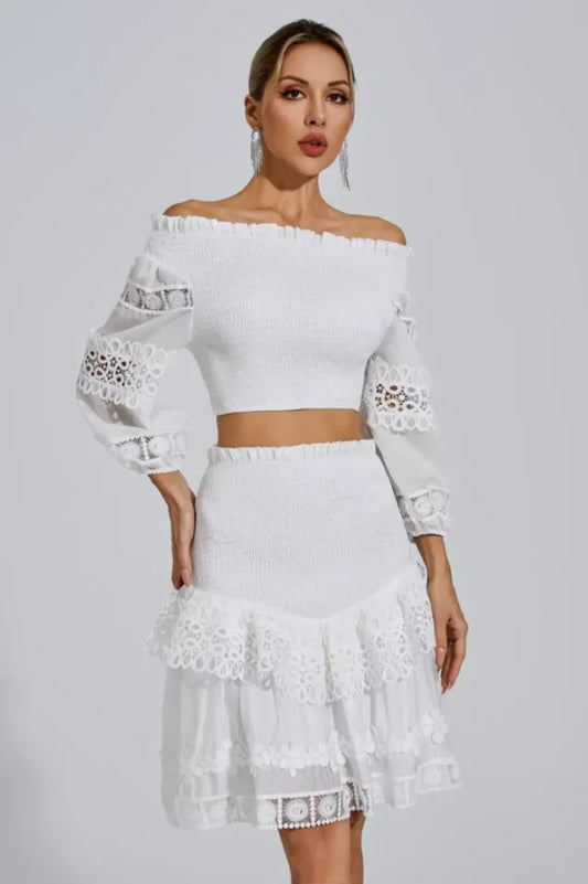 Woman wearing a white off-the-shoulder smocked crop top and a white tiered lace skirt
