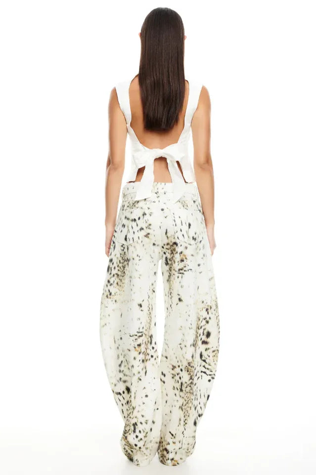 Model wearing a white sleeveless top and wide-leg printed pants, back view showing bow detail.