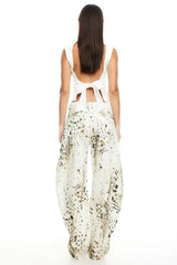 Model wearing a white sleeveless top and wide-leg printed pants, back view showing bow detail.