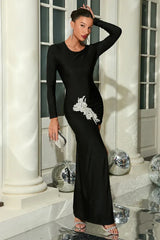 Full-length shot of a woman in a black formal dress featuring a dramatic slit and sparkling accents.