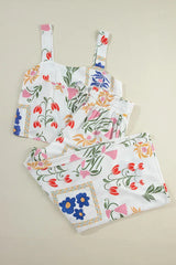 A woman models a white floral print two-piece set, consisting of a square-neck cropped tank top and high-waisted wide-leg pants.