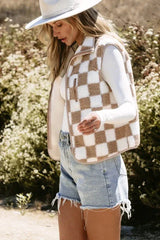 Woman wearing a brown and white checkerboard fleece vest over a white long-sleeved shirt and light blue denim shorts, showing side profile.