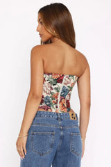 Back view of a woman in a strapless floral tapestry corset with zip closure and blue jeans