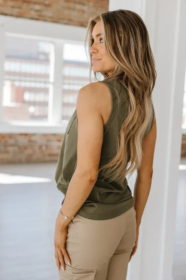 Back view of a woman wearing a green sleeveless henley top.