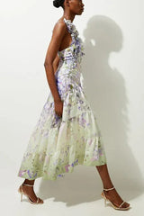 Side view of a woman in a floral print midi dress with ruffled straps and a tiered skirt.