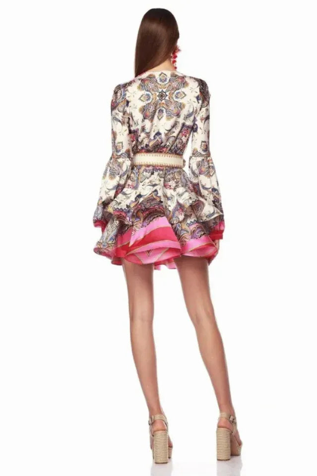 back view of a model wearing a paisley print mini dress with a v-neck and tiered hem