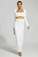 Woman wearing a white two-piece set with long sleeves and a square neckline, adorned with floral embellishments at the shoulders, bust, and waist, paired with a floor-length mermaid skirt.