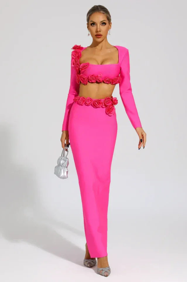 Woman in a bright pink two-piece evening gown with rose details, holding a small silver clutch.