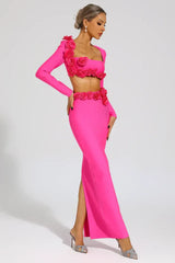 Side view of a woman in a bright pink two-piece evening gown featuring a square neckline, long sleeves, rose embellishments, and a floor-length mermaid skirt with a prominent slit.