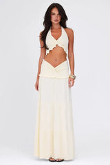 Model wearing a cream-colored two-piece set with a halter neck crop top and a tiered maxi skirt, front view