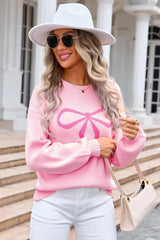 Woman wearing a pink knit sweater with a pink bow graphic, white hat, and sunglasses.