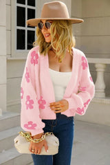 Woman wearing a pink fluffy knit cropped cardigan with a floral print, blue jeans, and a tan fedora.