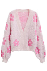A pink fluffy knit cropped cardigan with a floral print, laid flat.