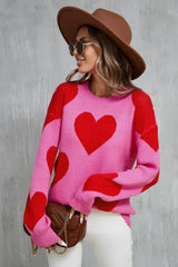 Woman wearing a pink sweater with a red heart print and a brown hat.