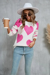 Woman wearing a white sweater with a pink heart print and holding a coffee cup.