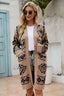 Woman wearing a tan geometric print long cardigan, white t-shirt, denim shorts, and sunglasses