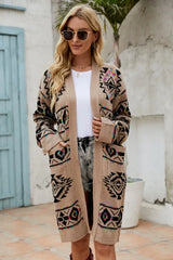 Woman wearing a tan geometric print long cardigan, white t-shirt, denim shorts, and sunglasses