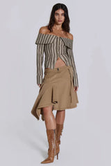 Full body shot of a model in an off-the-shoulder striped top, tan skirt, and brown boots