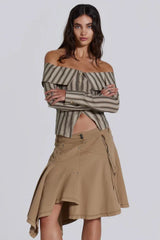 Model wearing an off-the-shoulder striped top and a tan skirt, arms crossed