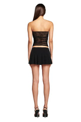 Back view of a woman wearing a black strapless lace tube top and a black mini skirt.