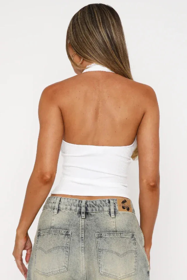Back view of a woman wearing a white ribbed halter top, showing the open back design.