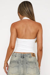 Back view of a woman wearing a white ribbed halter top, showing the open back design.