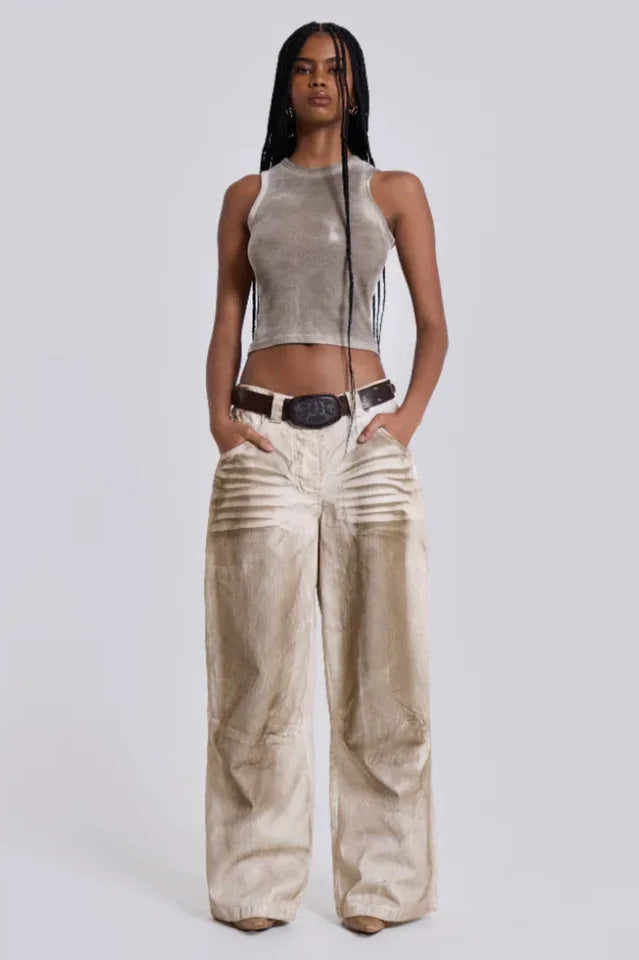 Model with hands in pockets wearing wide-leg light wash jeans and a cropped tank top.