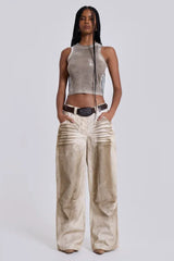 Model with hands in pockets wearing wide-leg light wash jeans and a cropped tank top.