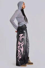 Side view of model wearing wide leg jeans with tribal print and a grey hoodie