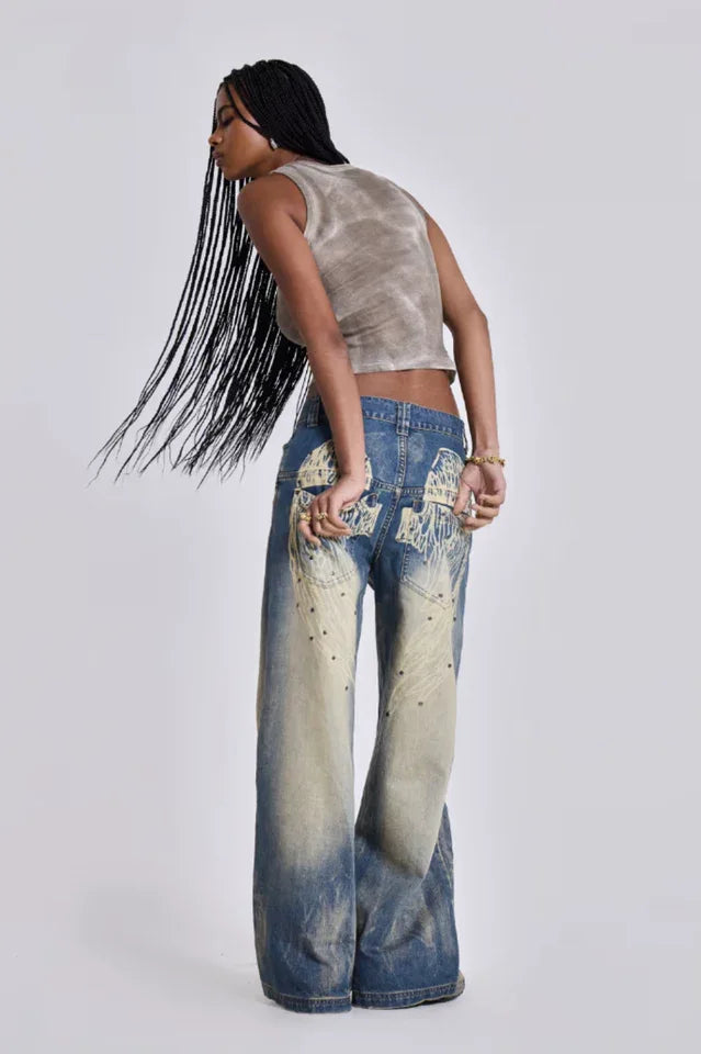 Model wearing wide leg jeans with a grey tank top and a denim bag, back view showing graphic detail.