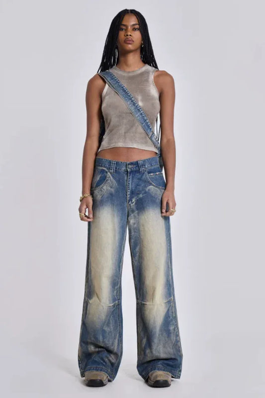 Model wearing wide leg jeans with a grey tank top and a denim bag, front view.