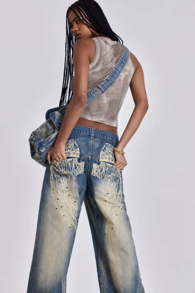 Model wearing wide leg jeans with a grey tank top and a denim bag, side back view showing graphic detail.