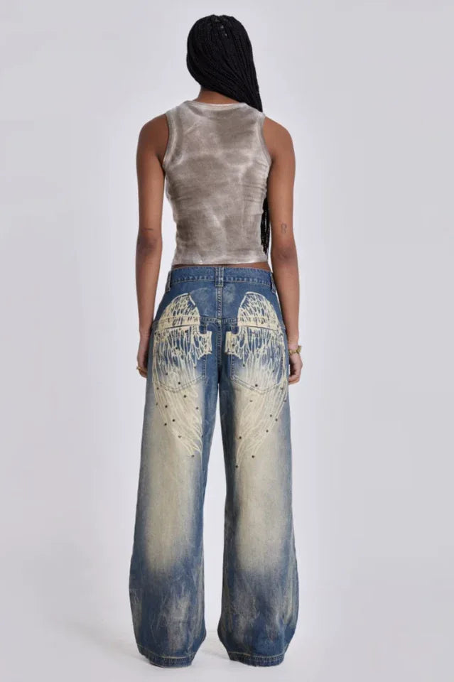 Model wearing wide leg jeans with a grey tank top, back view showing graphic detail.
