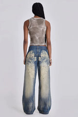 Model wearing wide leg jeans with a grey tank top, back view showing graphic detail.