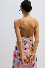 Back view of a woman in a pink sequined floral gown with gold chain straps, showing the open back.