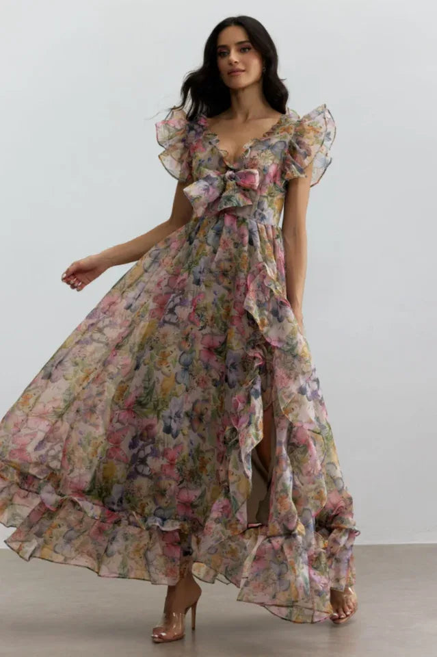 Woman in a flowing floral print chiffon gown with ruffled trim, showcasing the movement of the fabric.
