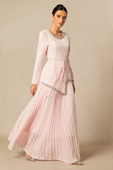 Woman in a light pink, long-sleeved formal dress with a pleated skirt, shown in motion.