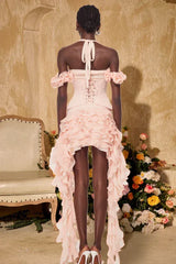 Back view of a model wearing a pink ruffled corset dress with a halter neckline and high-low hemline.