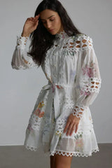 Close-up of a woman's face and upper body in a white floral lace dress