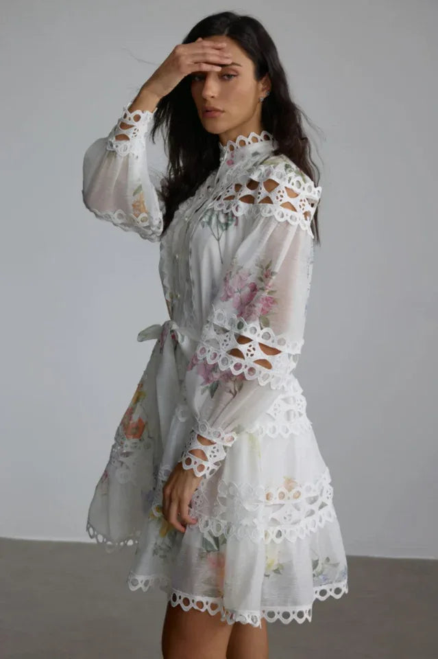Side view of a woman in a white floral dress with cut-out details on the neckline and sleeves
