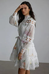 Side view of a woman in a white floral dress with cut-out details on the neckline and sleeves